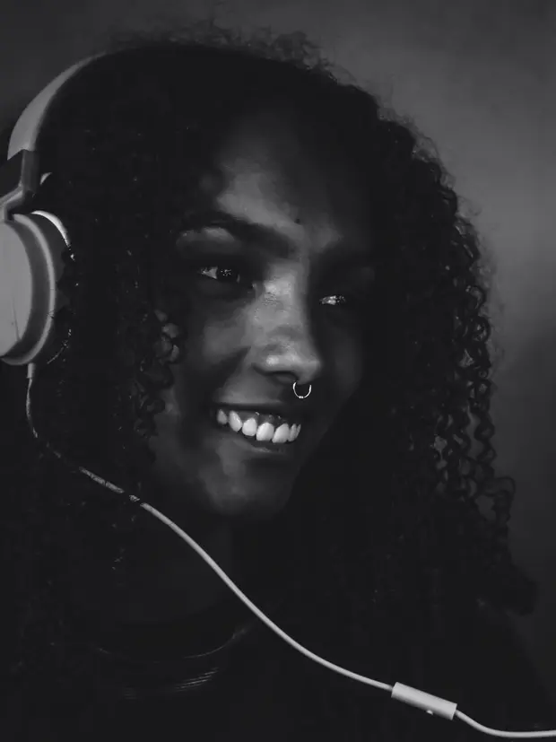 Retrato em preto e branco de uma mulher sorrindo, de fones de ouvido