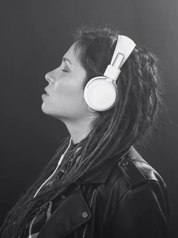 Retrato em preto e branco de uma mulher de perfil, com fones de ouvido brancos